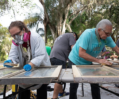 Competitors working on window sash on outdoor tables