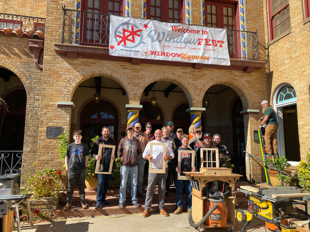 Participants holding restored window sash in front of the Uvalde Grand Opera House under a WindowFest banner